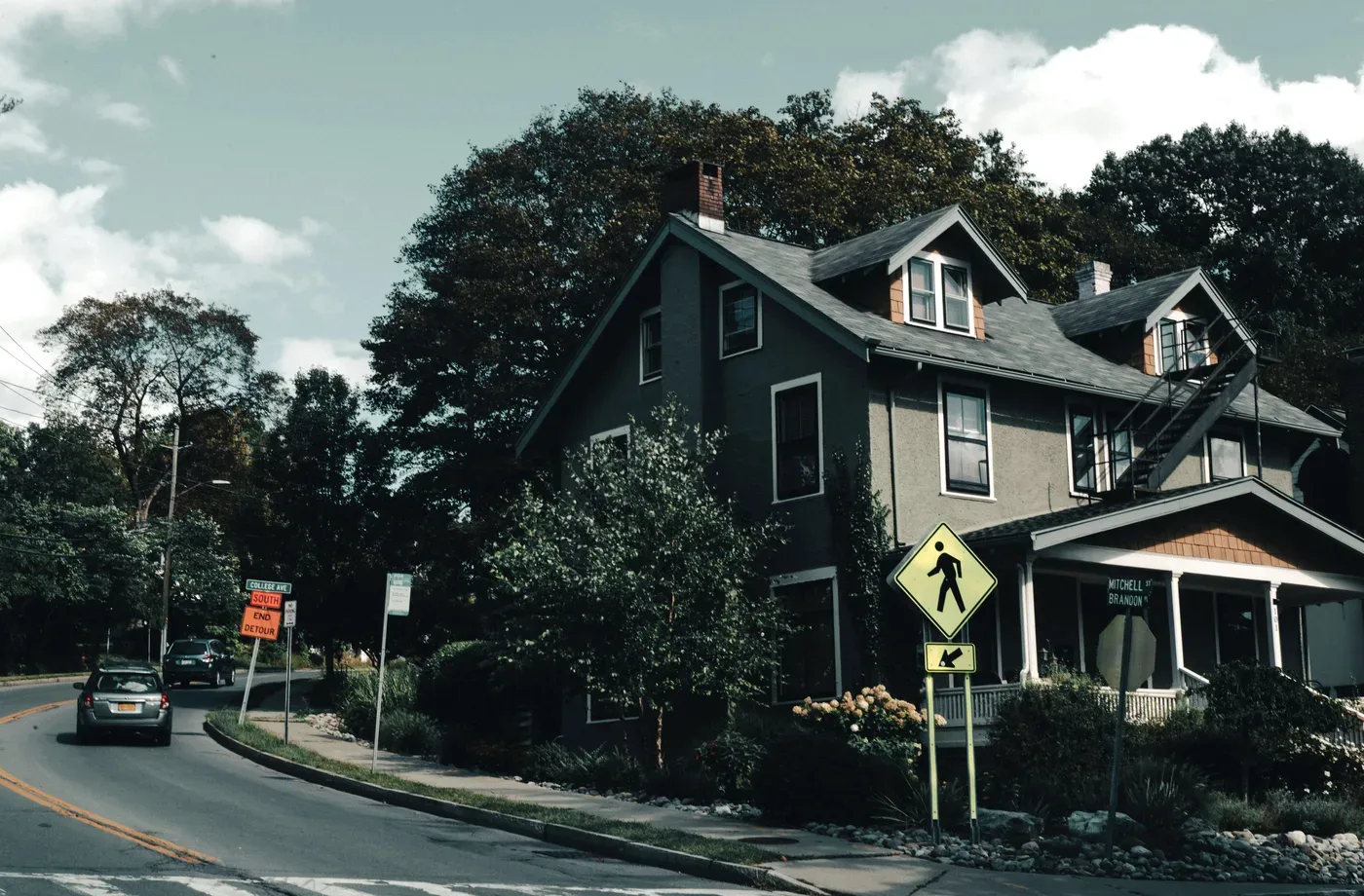 Older residential home on a tree-lined street with several visible windows
